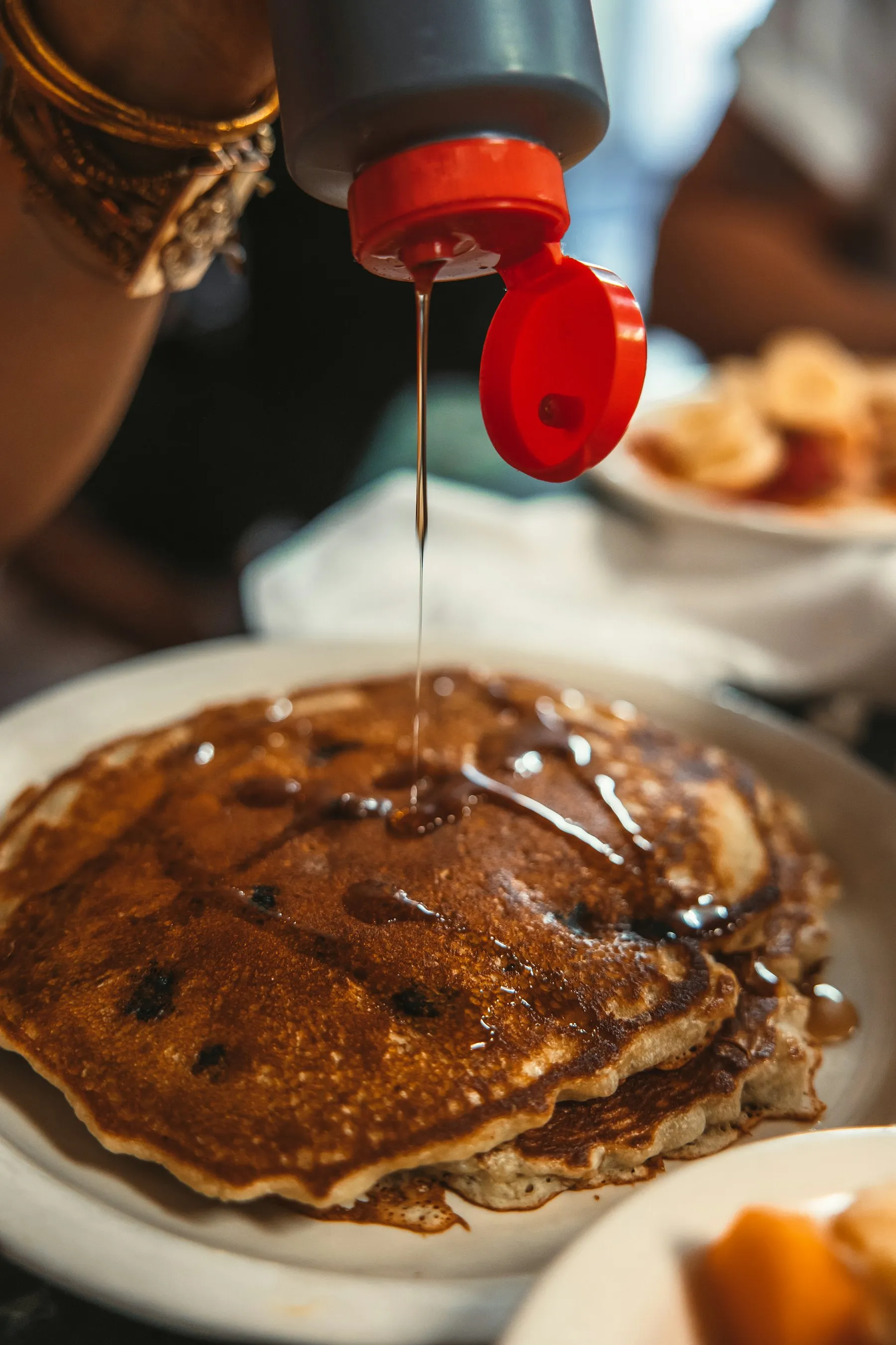 Close-up of syrup being poured over a stack of pancakes